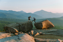 Man Helping Woman Across Boulder, Pitchoff?Mountain, Adirondack Mountains, New York State, USA