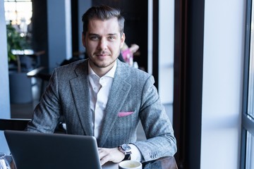 Canvas Print - Full concentration. Good looking young man in full suit using computer while sitting in the cafe