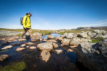Male Hiker Crossing Creek In Norway