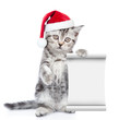 © Ermolaev Alexandr - Funny kitten in red christmas hat with empty list. isolated on white background