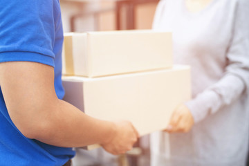 parcel delivery man of a package through a service. and close up hand customer female accepting a delivery of boxes from delivery man postal send direct to home.