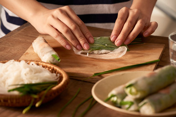 Fresh spring rolls with shrimps with cooker hands on background