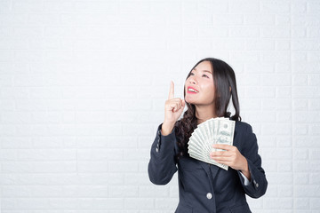 Wall Mural - A young businesswoman holds a dollar note on a white brick wall background.