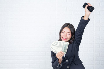 Wall Mural - A young businesswoman holds a dollar note on a white brick wall background.