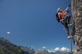Pretty, female climber on a via ferrata - climbing on a rock in Swiss Alps