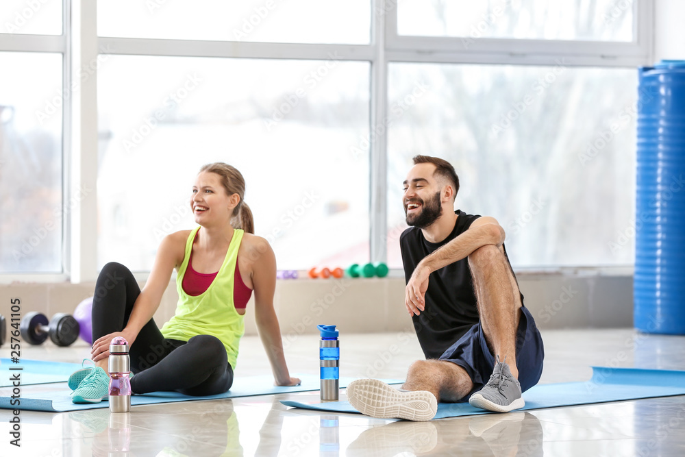 Sporty young people resting after training in gym