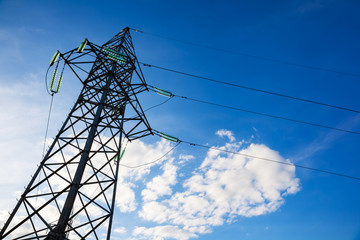 Wall Mural - High voltage electricity pylon and transmission power line on the blue sky and white clouds on the background. Parts of electrical equipment and high voltage power line insulators.