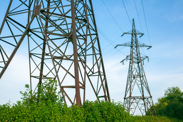 Wall Mural - High voltage electricity pylon and transmission power line on the blue sky and white clouds on the background. Parts of electrical equipment and high voltage power line insulators.