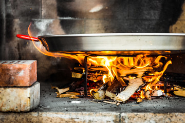 Cooking and making a traditional Spanish Paella over open fire.