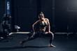 © Dusan Petkovic - Young muscular Caucasian fit brunette stretching leg in gym. Side view, night workout concept.