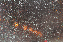 An Icy Windshield In A Car In The Golden Light Of A Street Lamp.