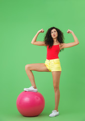 Wall Mural - Image of strong woman 20s wearing summer clothes doing exercises with fitness ball during aerobics