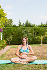 Wall Mural - Pregnant woman relaxing doing yoga outdoors