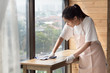 woman cleaner cleaning living room in apartment. portrait of asian woman cleaning staff doing housekeeping or domestic helper job. young adult asian woman model