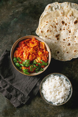 Wall Mural - Vegan vegetarian curry with ripe yellow jackfruit served in ceramic bowl with rice, coriander and homemade flatbread flapjack over dark metal background. Flat lay, space