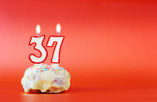 Thirty Seven Years Birthday. Cupcake With White Burning Candle In The Form Of Number 37. Vivid Red Background With Copy Space