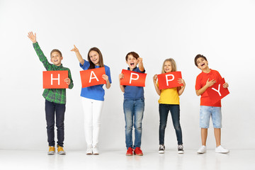  Friendship make us better. Group of happy smiling children with red banners making word isolated in white studio background. Education and advertising concept.