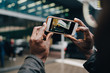 © Maskot - Cropped hands of businessman photographing building with smart phone in city