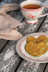 two heart shaped spinach pancakes on a wooden rustic backdrop