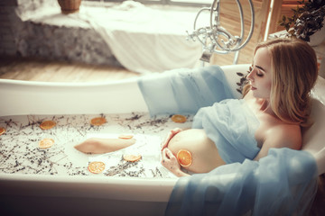 Wall Mural - Pregnant woman takes a bath with milk, lavender herbs and orange slices.