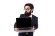 © alesmunt - Frowning bearded businessman with a laptop in hand, raising an eyebrow looking at the camera, isolated on white background
