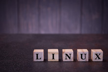The Word Linux On Wooden Cubes, On A Dark Background, Symbols Signs