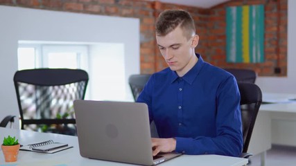 Aufkleber - young worker in startup company sitting at the white desk in loft office businessman focused looking on display computer entering data on pc at work daytime.