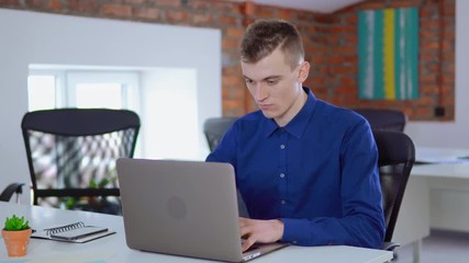 Aufkleber - businessman focused looking on display computer entering data on pc at work daytime young worker looking at the camera startup company sitting at the white desk in loft office.