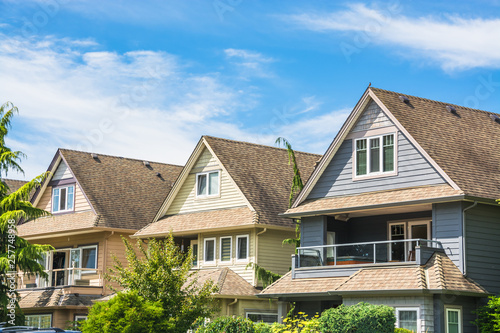 Fotomural Top of three residential houses on blue sky background