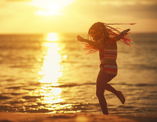 Wall Mural - . happy child girl in swimsuit with flying hair dancing on  beach at sunset.