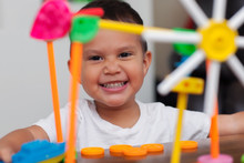 A Hispanic Boy With Big Smile While He Plays With Colorful Building Toys And Learns To Count With Elementary Manipulative Toys.