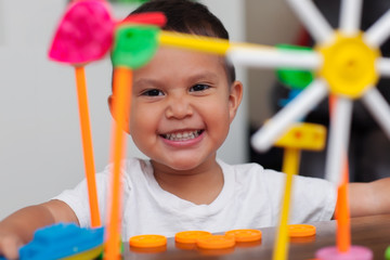 A hispanic boy with big smile while he plays with colorful building toys and learns to count with elementary manipulative toys.