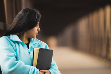 Wall Mural - Hispanic Woman Praying While Holding Bible On A Bridge