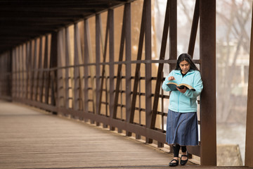 Wall Mural - Hispanic Woman Reading Bible On A Bridge