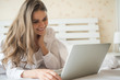 © Johnstocker - Happy Beautiful woman working on a laptop on the bed in the house