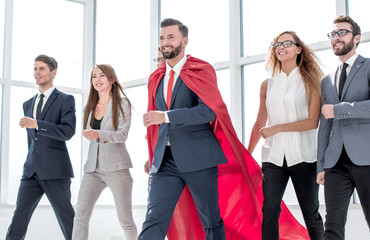 Wall Mural - businessman in a red cloak marching with the business team