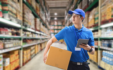 Deliveryman holding box and using digital tablet.