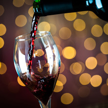  Pouring Red Wine Into The Glass. Golden Bokeh Background.