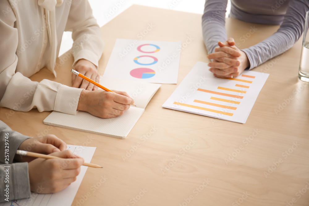 Colleagues sitting at table during business meeting in conference hall