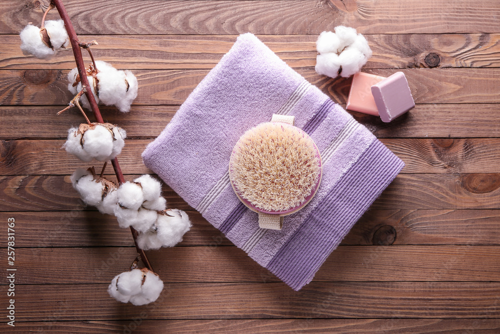 Massage brush with towel and soap on wooden table