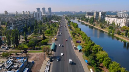 Aufkleber - aerial drone shot kyiv in ukraine road with driving cars along river with blue water daytime in summer season from down to up