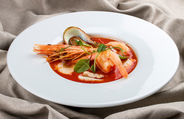 Wall Mural - French bouillabaisse fish soup with shrimp, mussels and scallop. In a white plate on a textile background