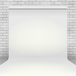 Empty white paper photo studio backdrop in room with white brick wall and concrete floor.
