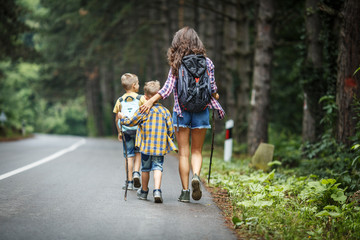 Wall Mural - mother and her little sons hiking by the rural country road.outdoor spring leisure concept.