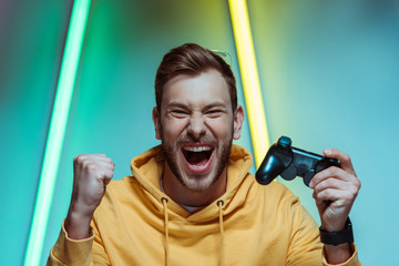  handsome and screaming man looking at camera and holding gamepad