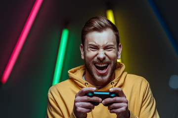 handsome and screaming man looking at camera and holding gamepad