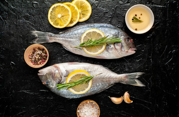 two fresh raw Dorado fish with spices and olive oil on a stone background.