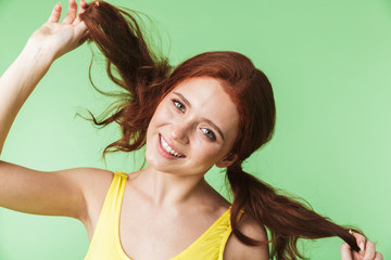 Wall Mural - beautiful happy young redhead girl posing isolated over green wall background.