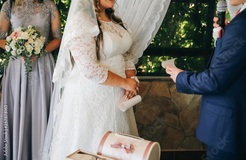 Curvy Bride In White Lace Dress And A Groom Wedding Couple At The Ceremony Man And Wife Giving Marriage Vows Engagement Rings Outdoors Flowers Decoration Buy This Stock Photo And Explore