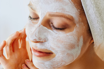 Wall Mural - beautiful young woman with facial mask on her face. skin care and treatment, spa, natural beauty and